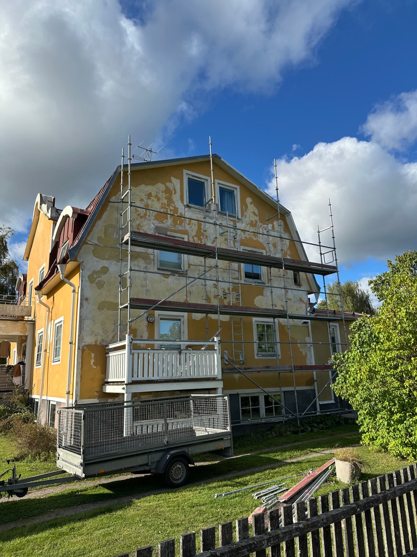 Family house gable under full scaffold during facade renovation, old render stripped back
