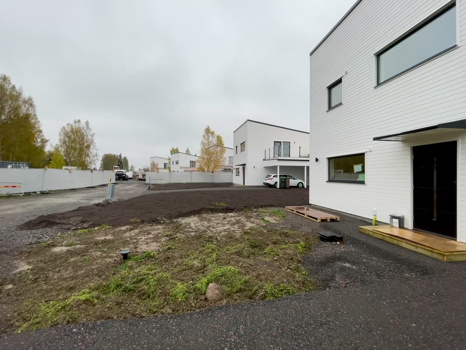 Finished white timber-clad two-storey family house with black entrance door and new plot