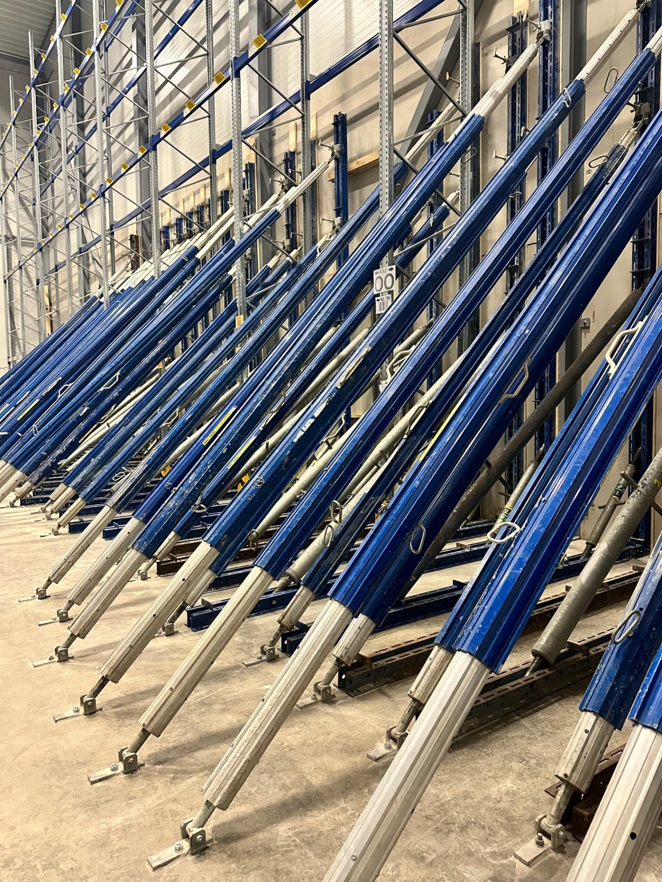 Row of adjustable props and beams staged along the warehouse wall