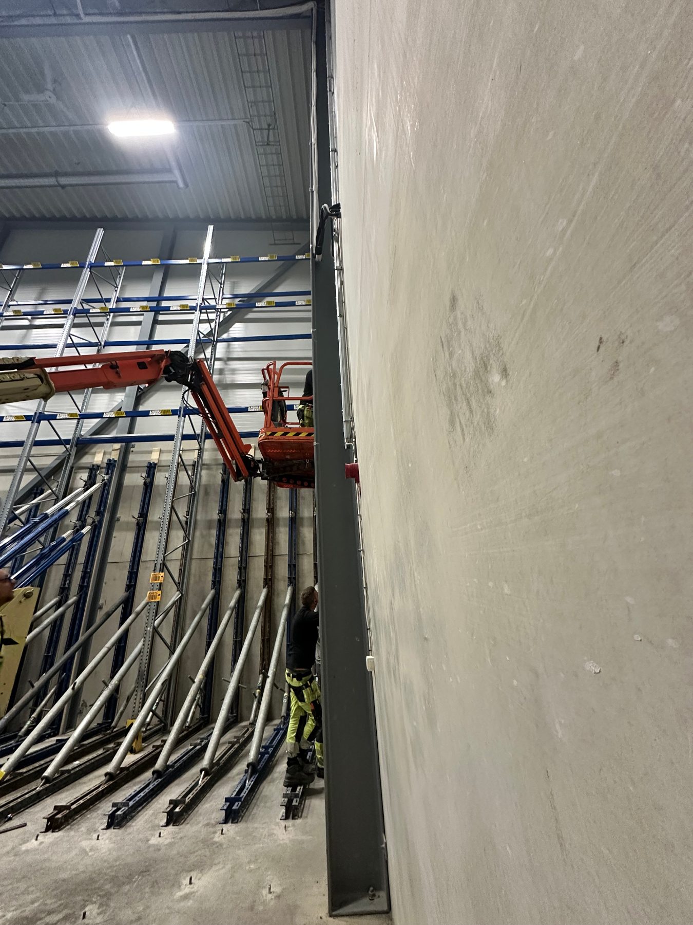 Boom lift used to fix bracing at height against the concrete wall