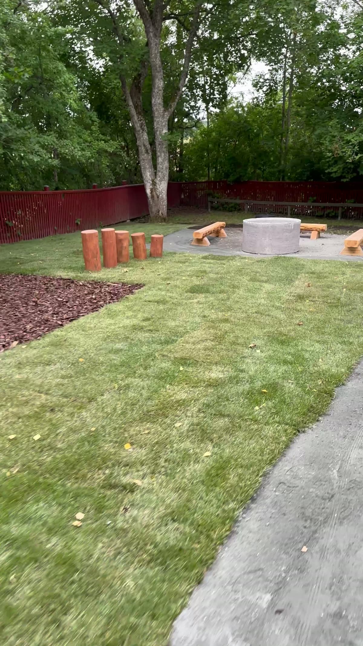 Kindergarten lawn with timber balance posts and a circular paved feature area