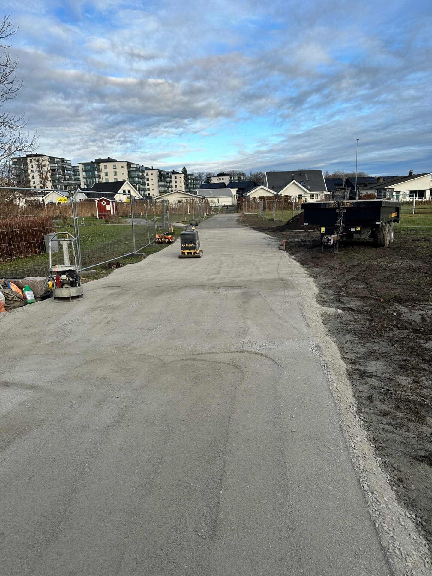 Compacted gravel pedestrian path between fenced construction areas