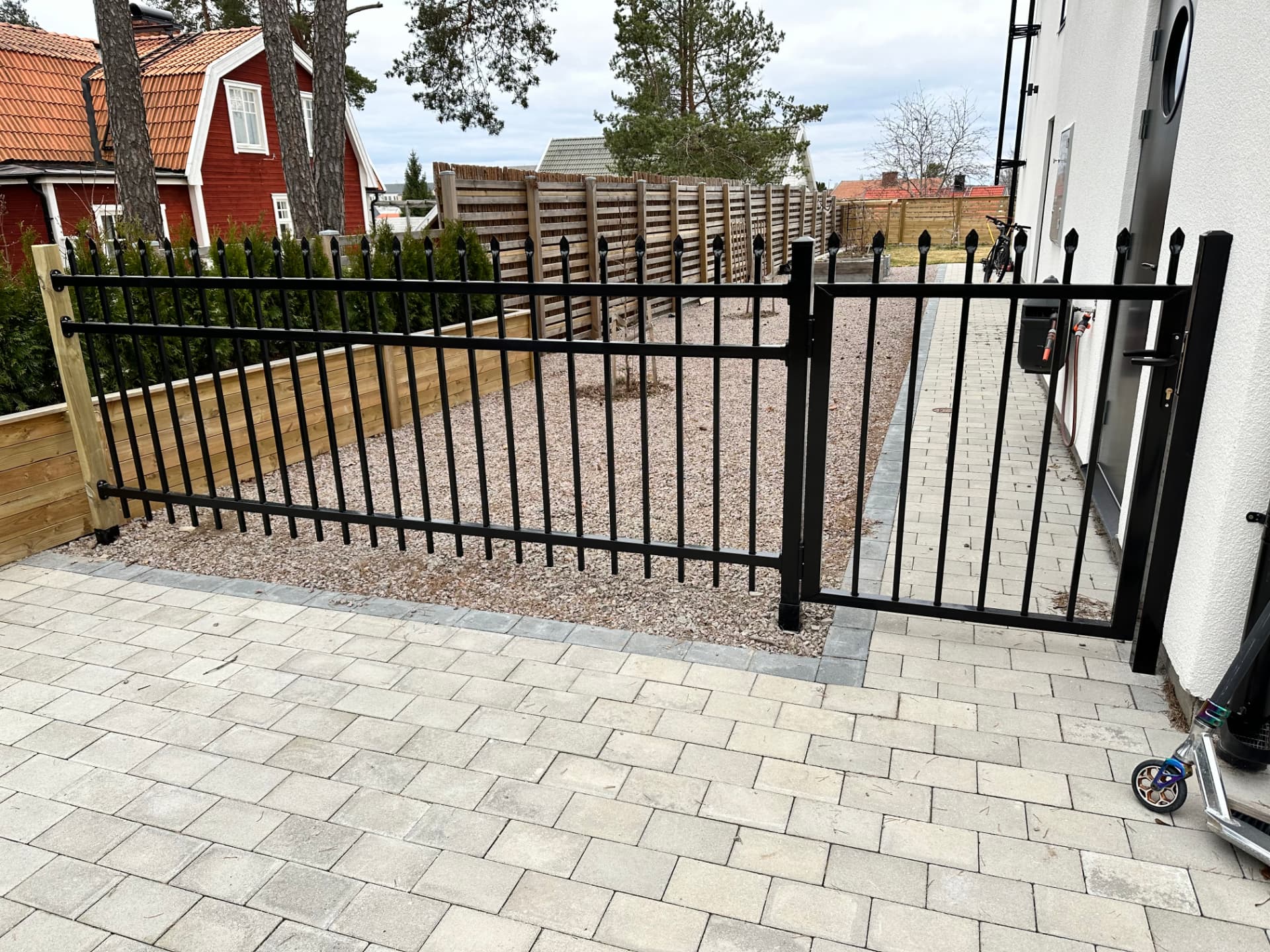 Completed private driveway with stone paving, black metal gate and planted garden beds