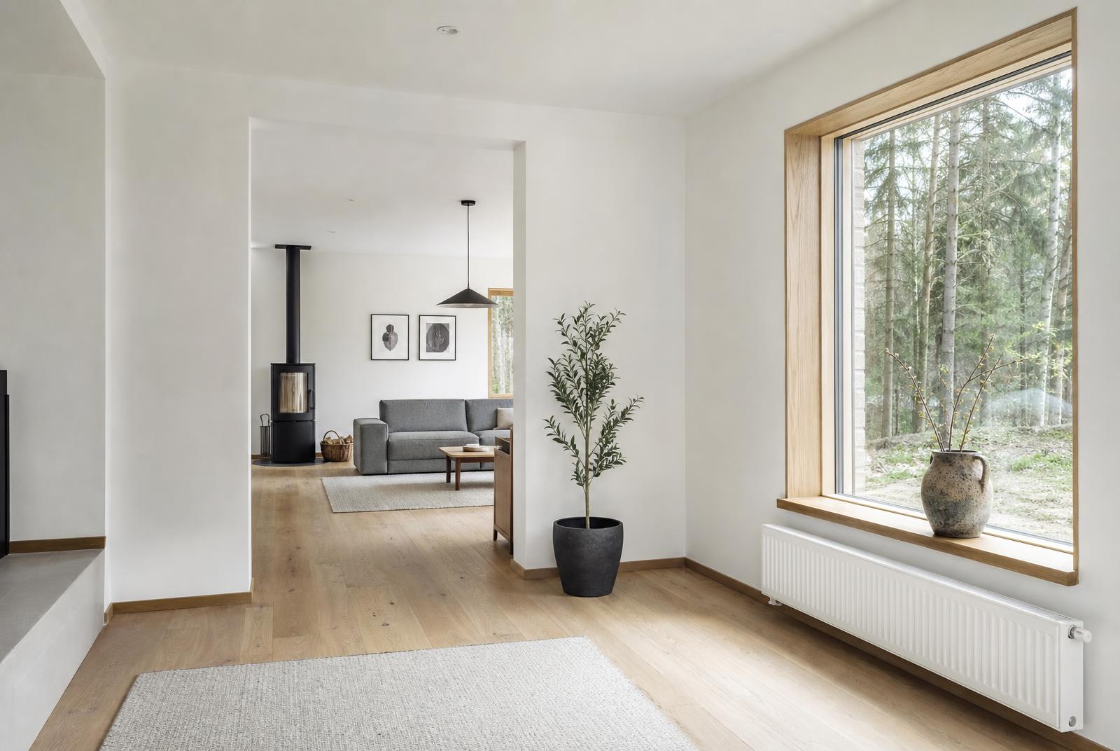 Renovated open-plan living room with new oak flooring, fresh white plaster and a large timber-framed window