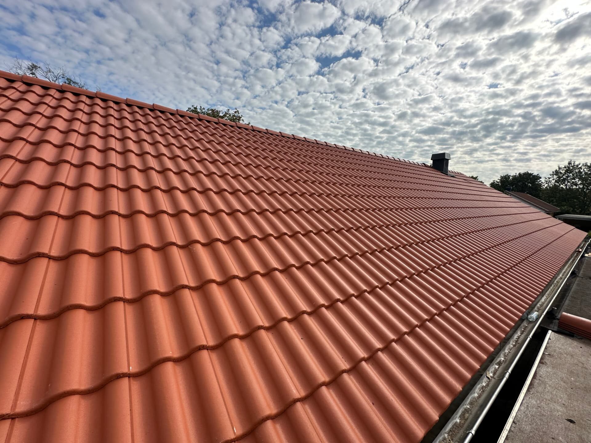 Completed tiled roof slope with clean ridge line and new guttering