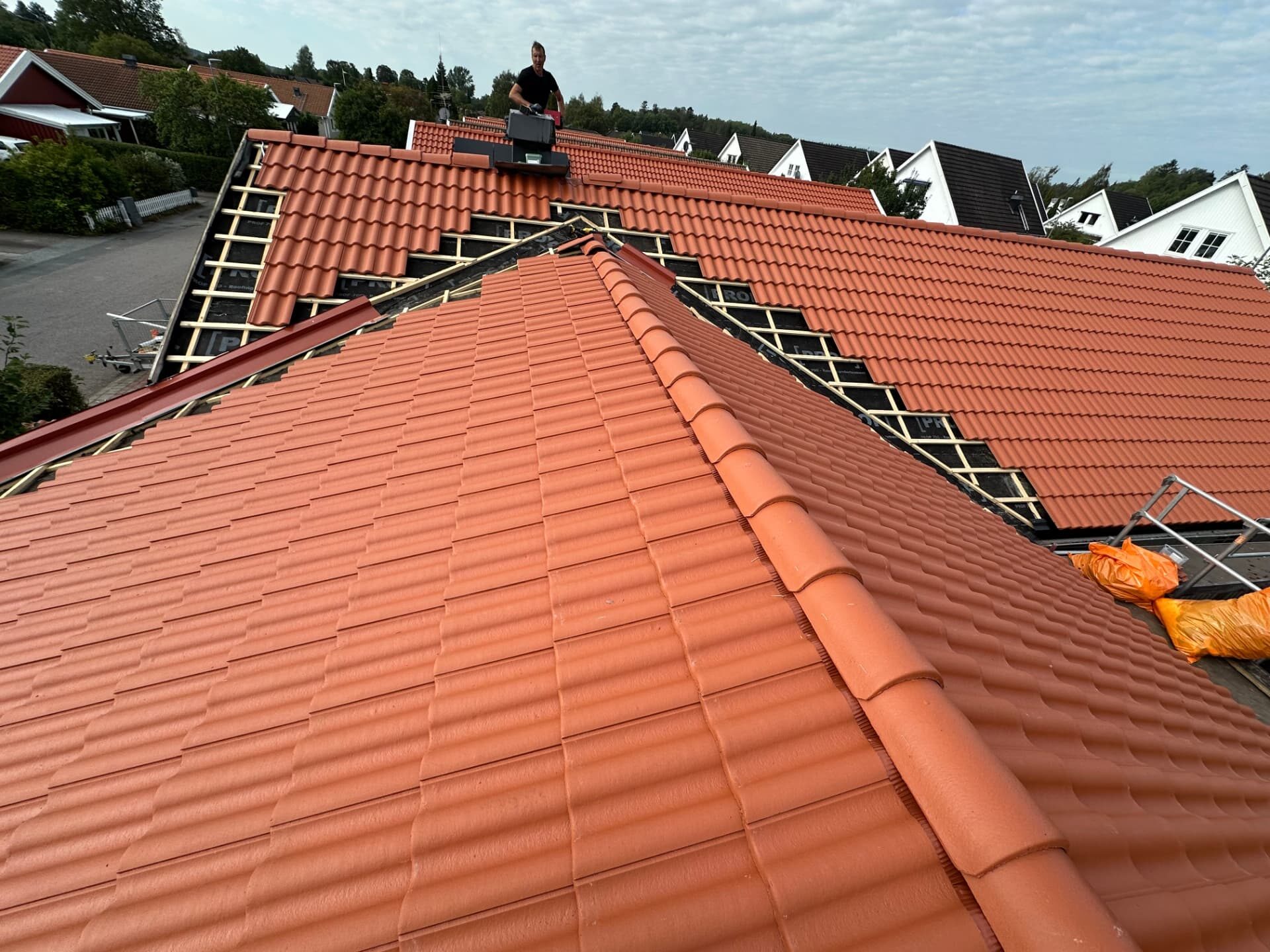 GLD Group roofer working at the ridge of a tiled roof on a residential street
