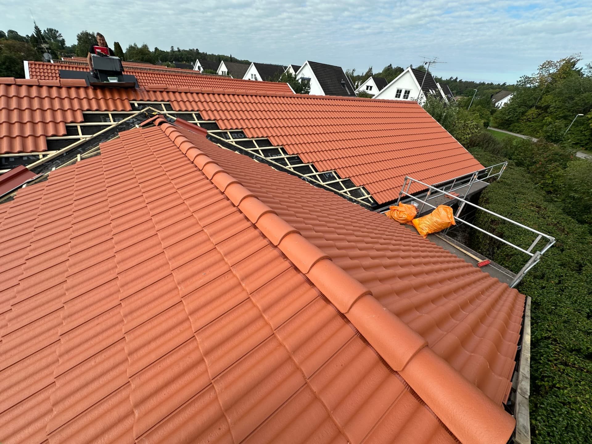 Overview of a house roof with the near slope finished and the far slope in progress