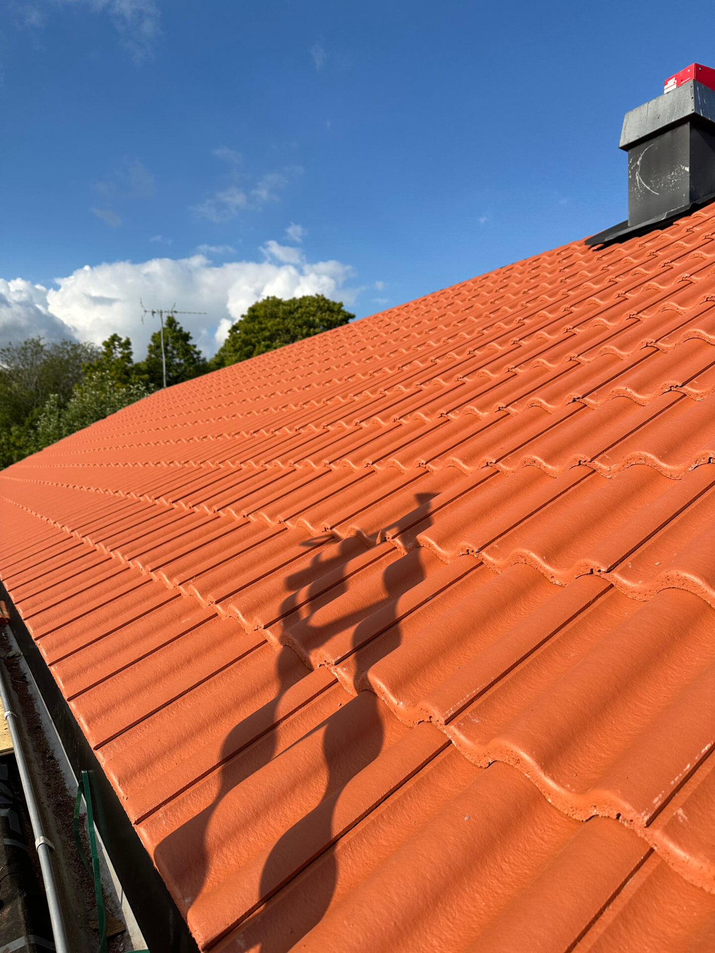Completed terracotta tile roof with flashing around the chimney