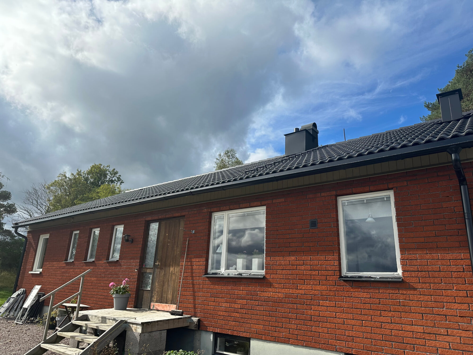 Brick family home in Sweden with a newly replaced dark concrete tile roof and two chimneys