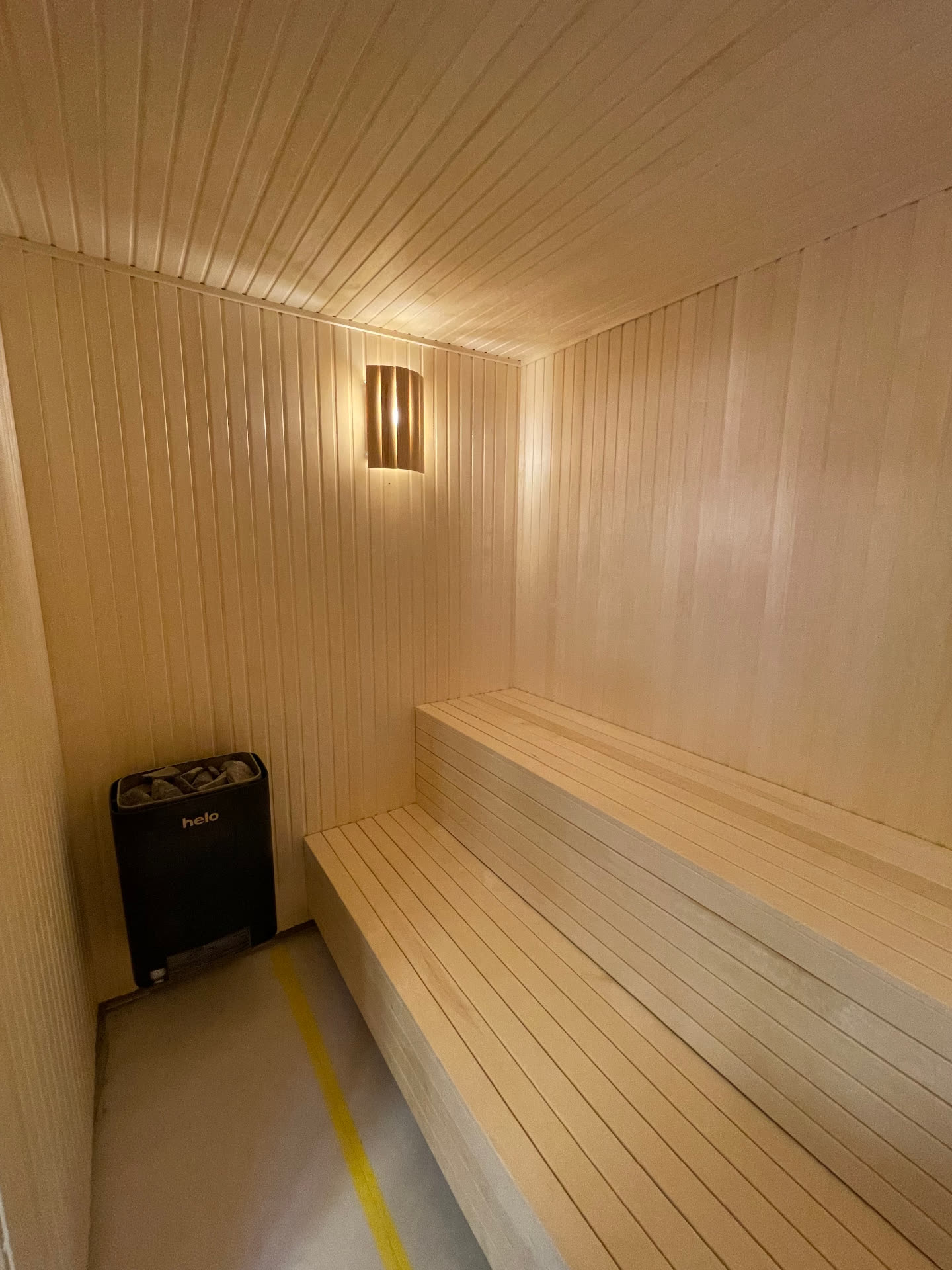 Aspen-lined sauna room with L-shaped benching and a wall-mounted electric heater