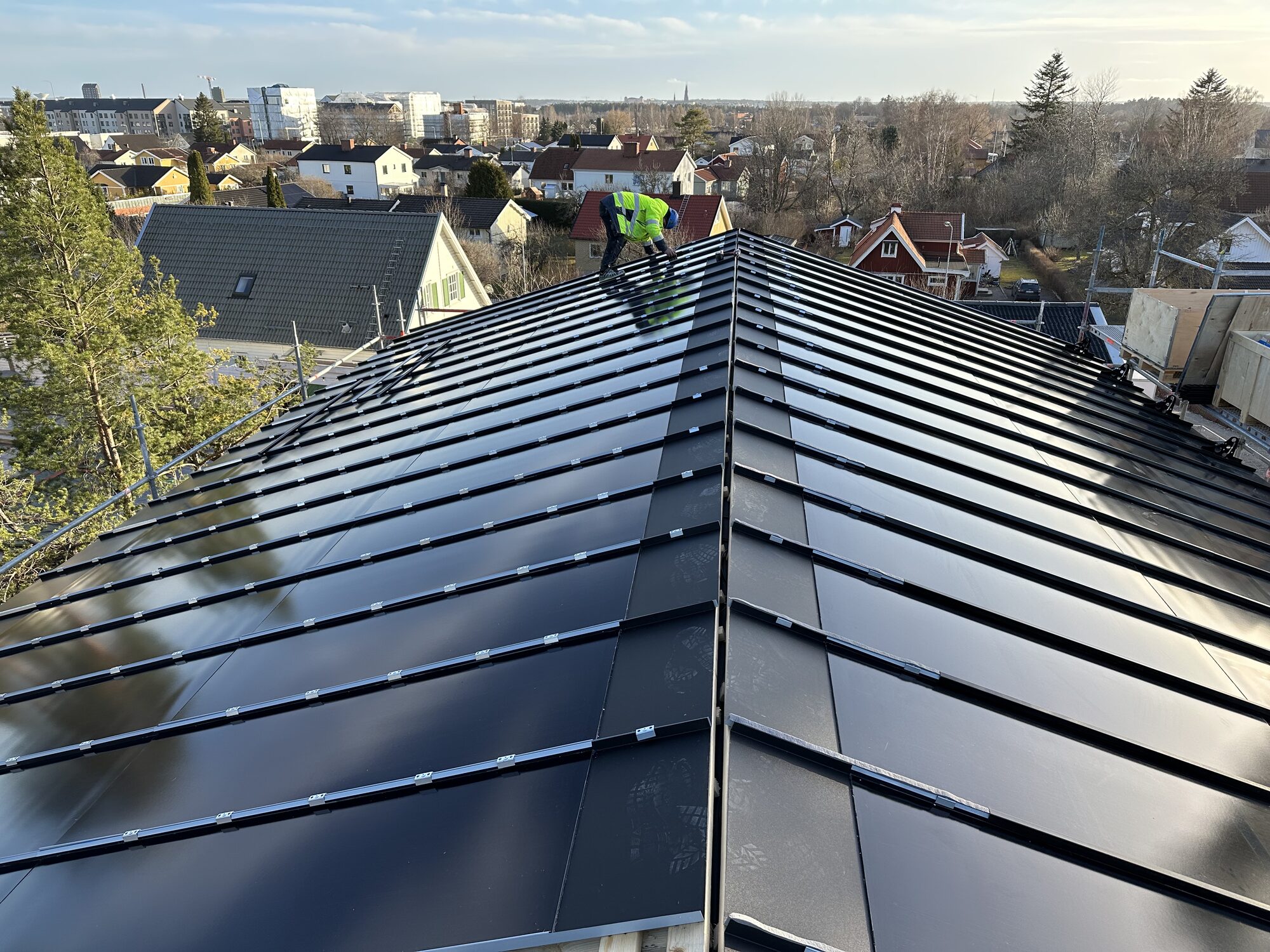 Standing seam metal roof in Sweden with integrated black solar panels flush in the roof plane