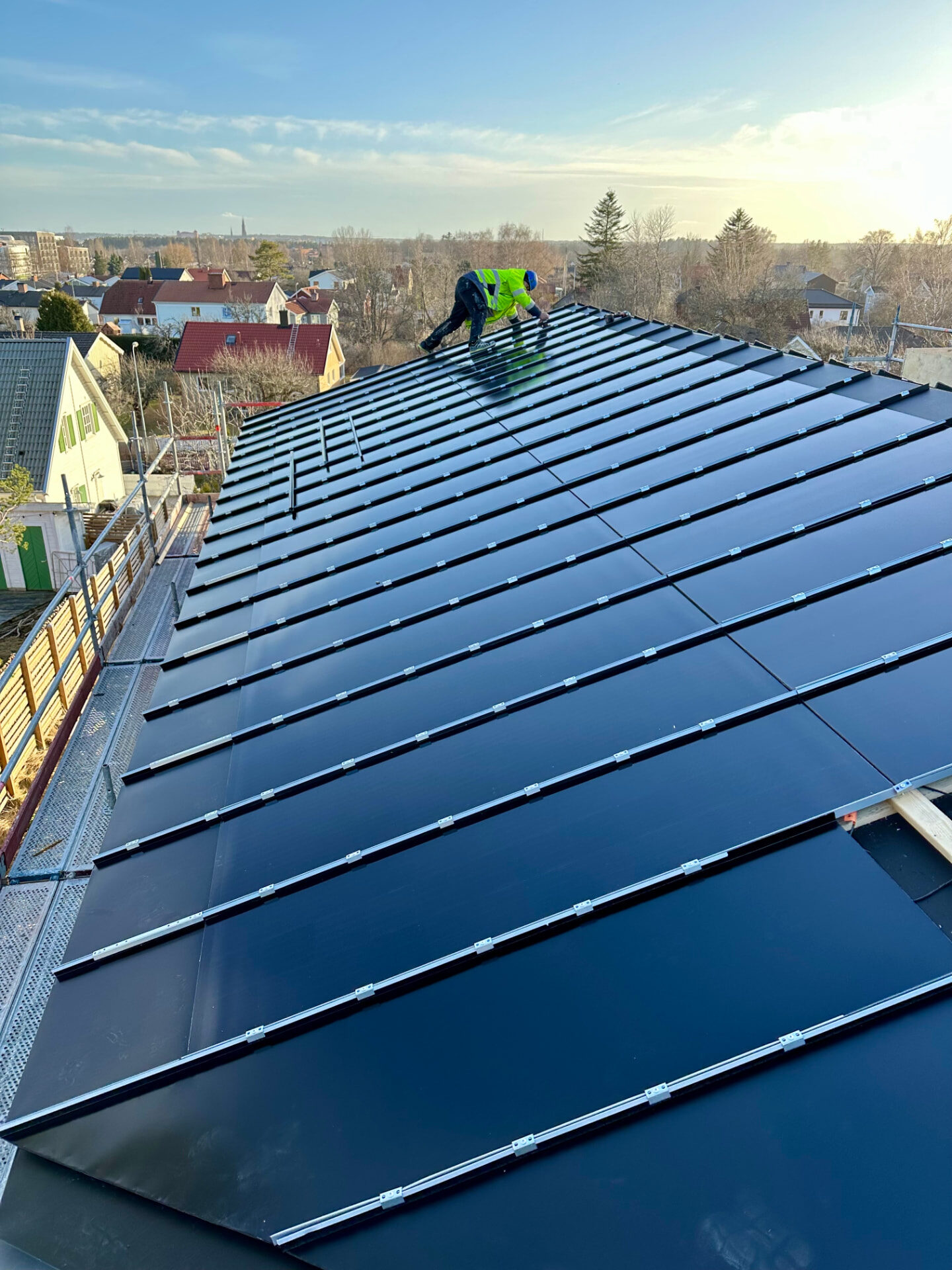 Installer working across the completed black roof with integrated solar