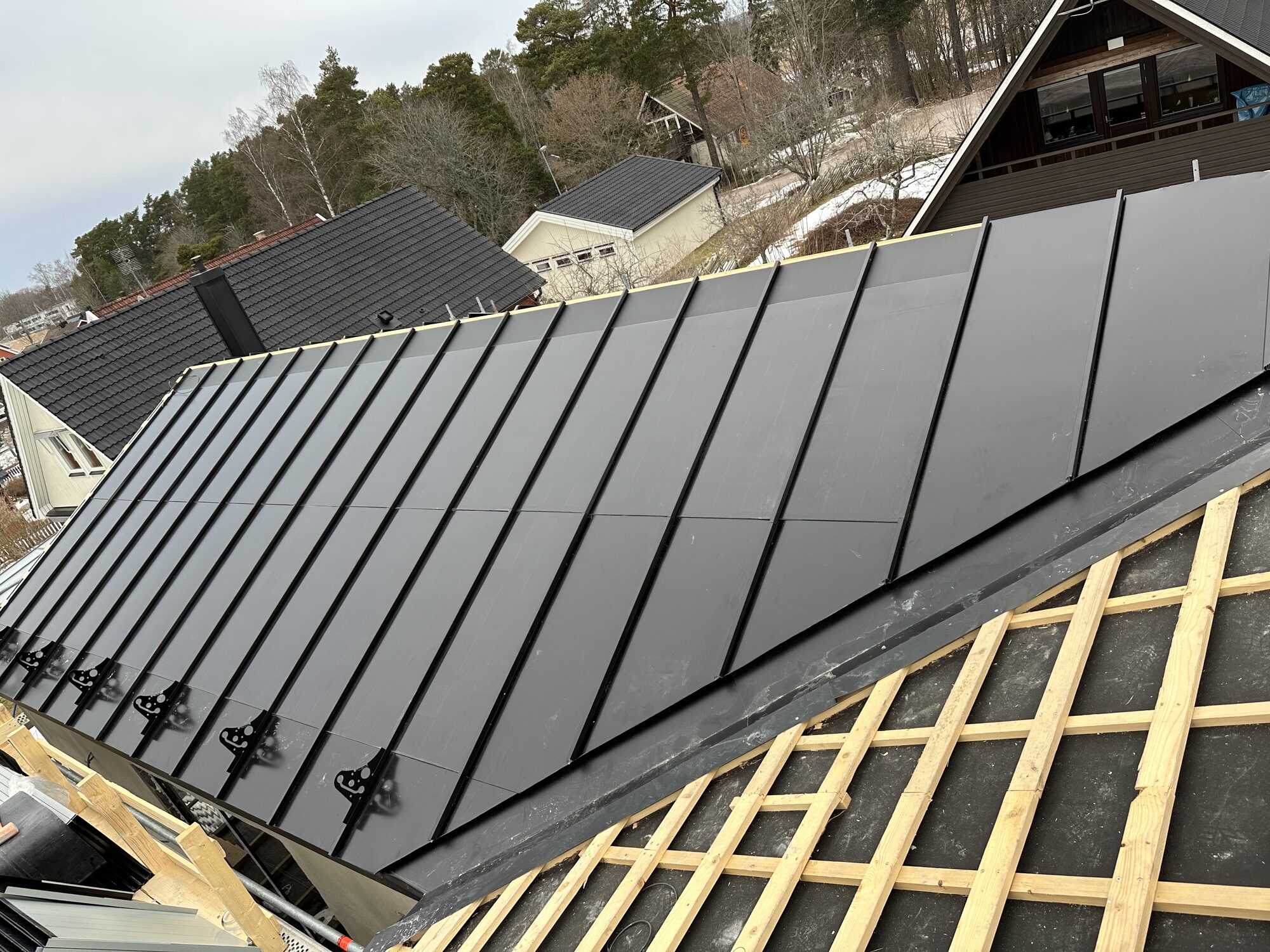 Close view of thin black in-roof solar panels sitting flush between standing seams