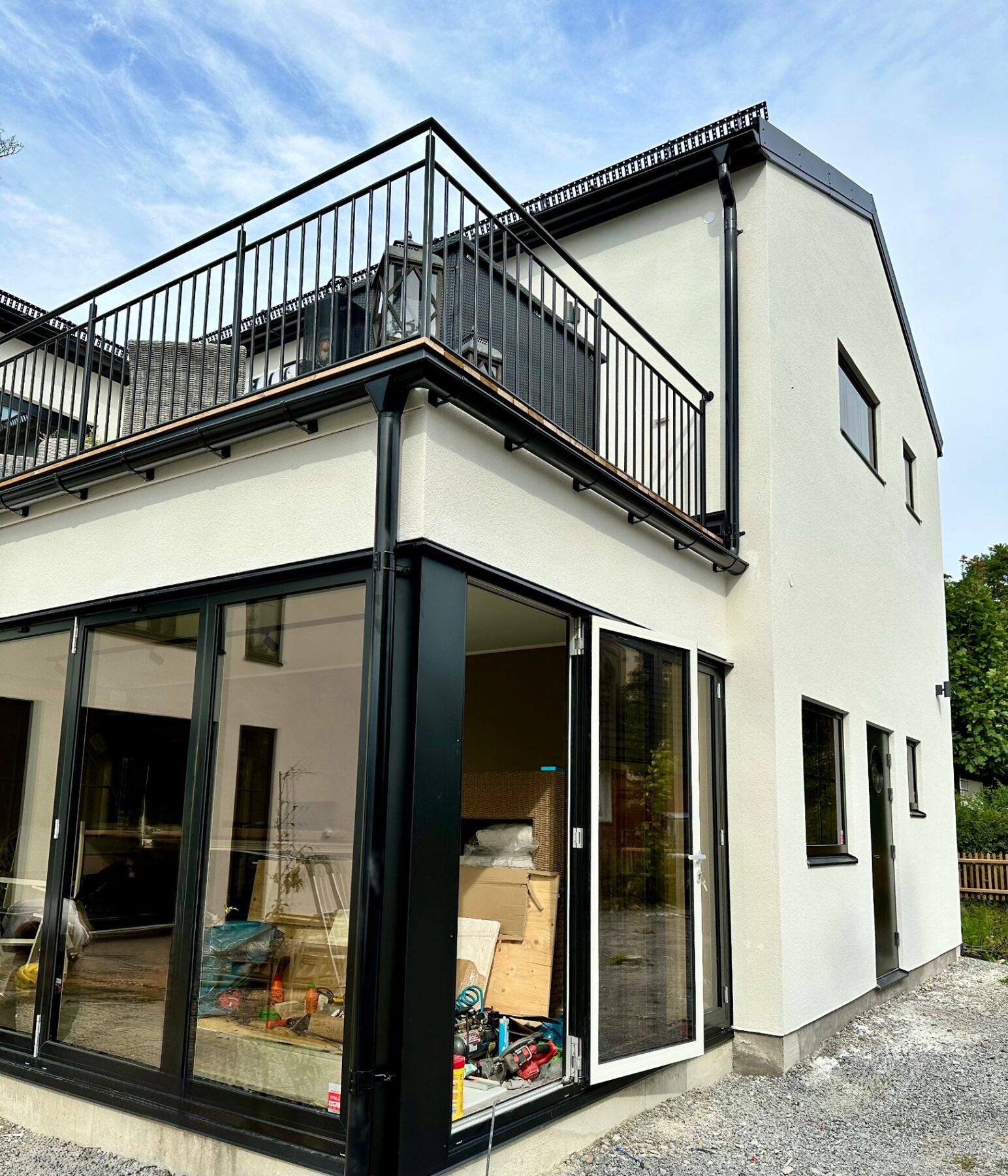 Upper timber balcony terrace with black steel railing on a white rendered villa