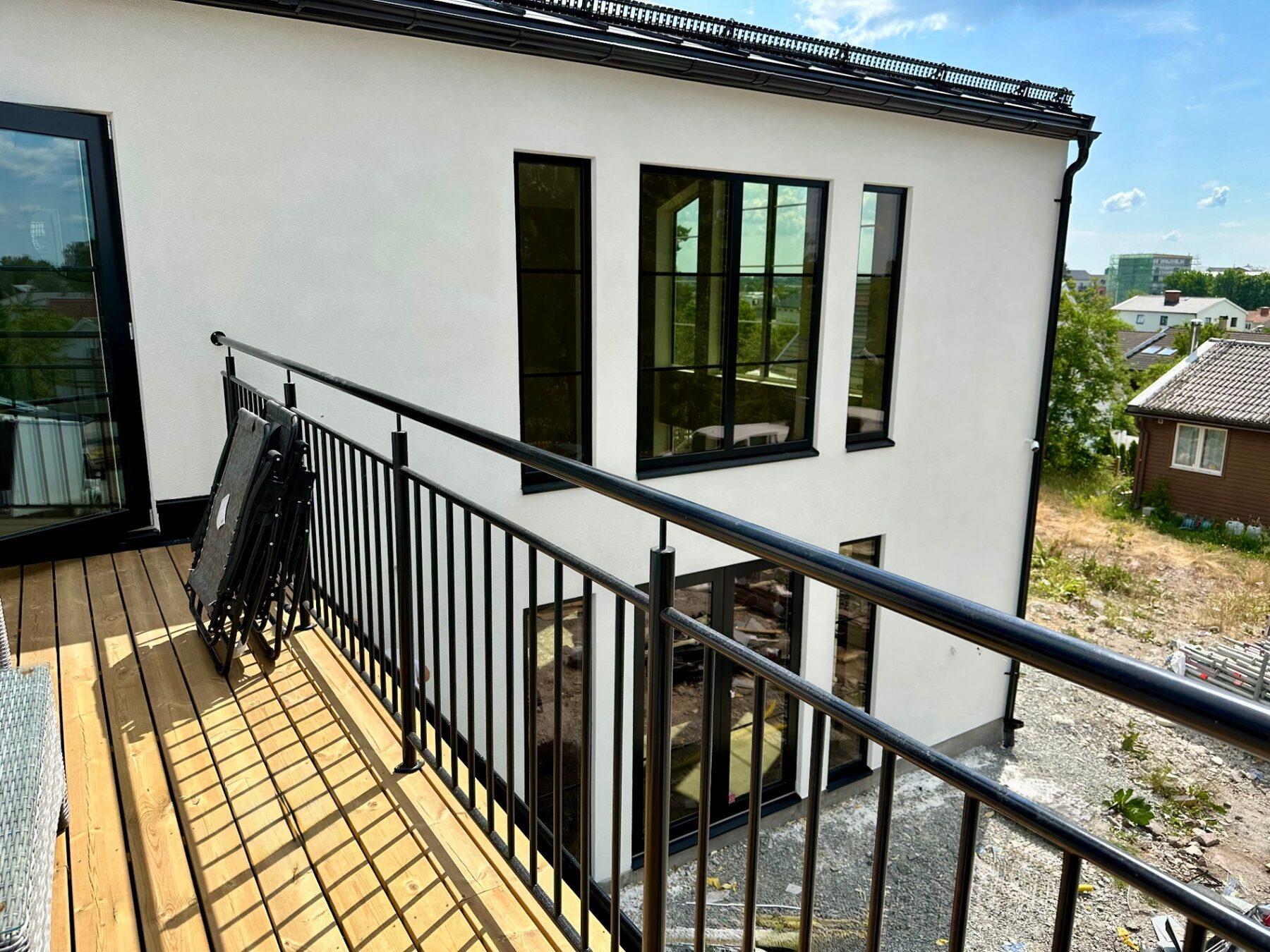 Narrow balcony deck with black steel railing overlooking the villa facade