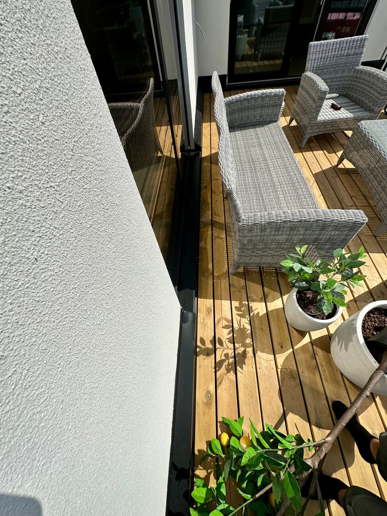 Terrace decking running to a glass balustrade and rendered corner wall