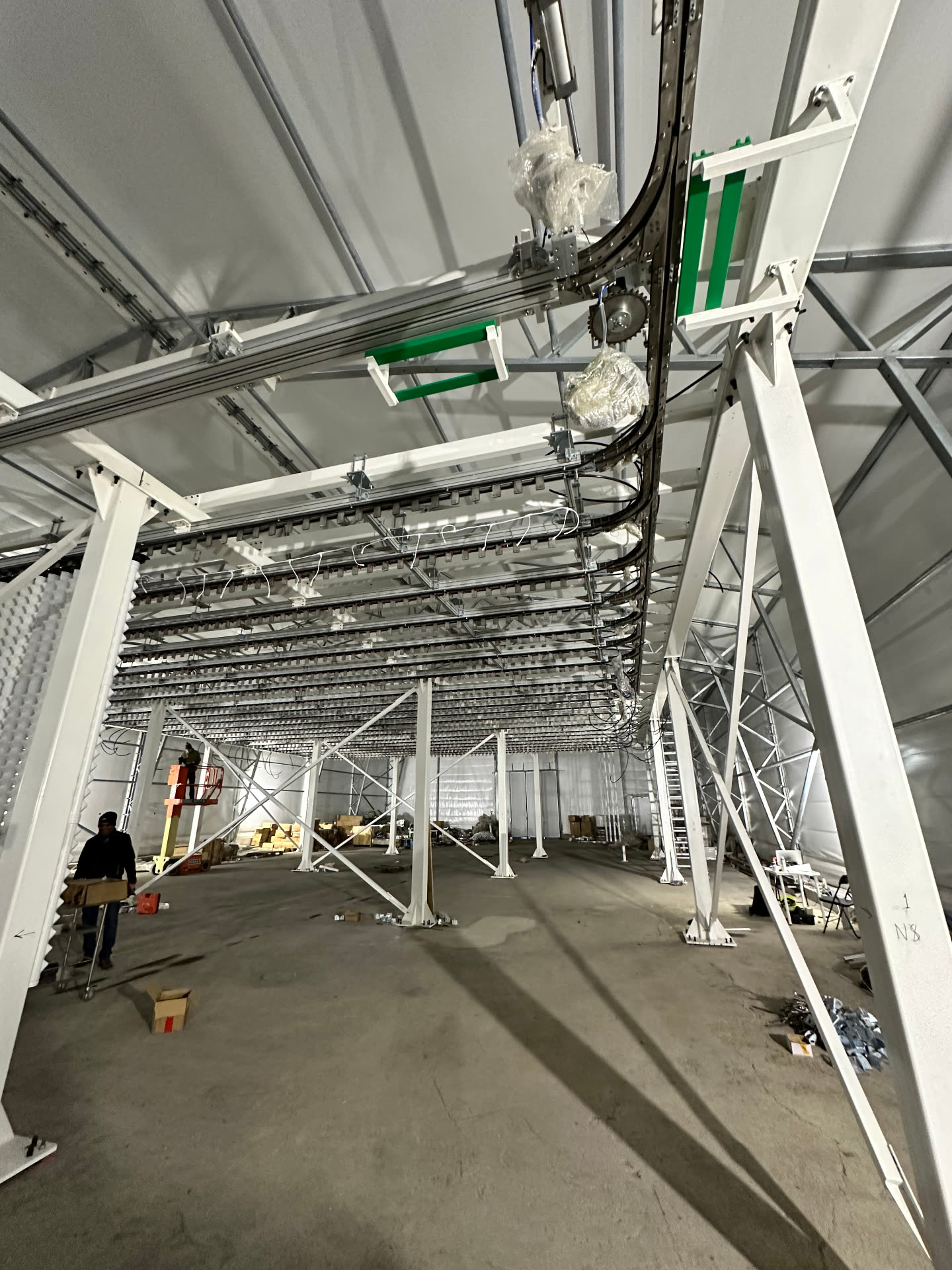 Overhead conveyor grid installed across a white steel-framed production hall
