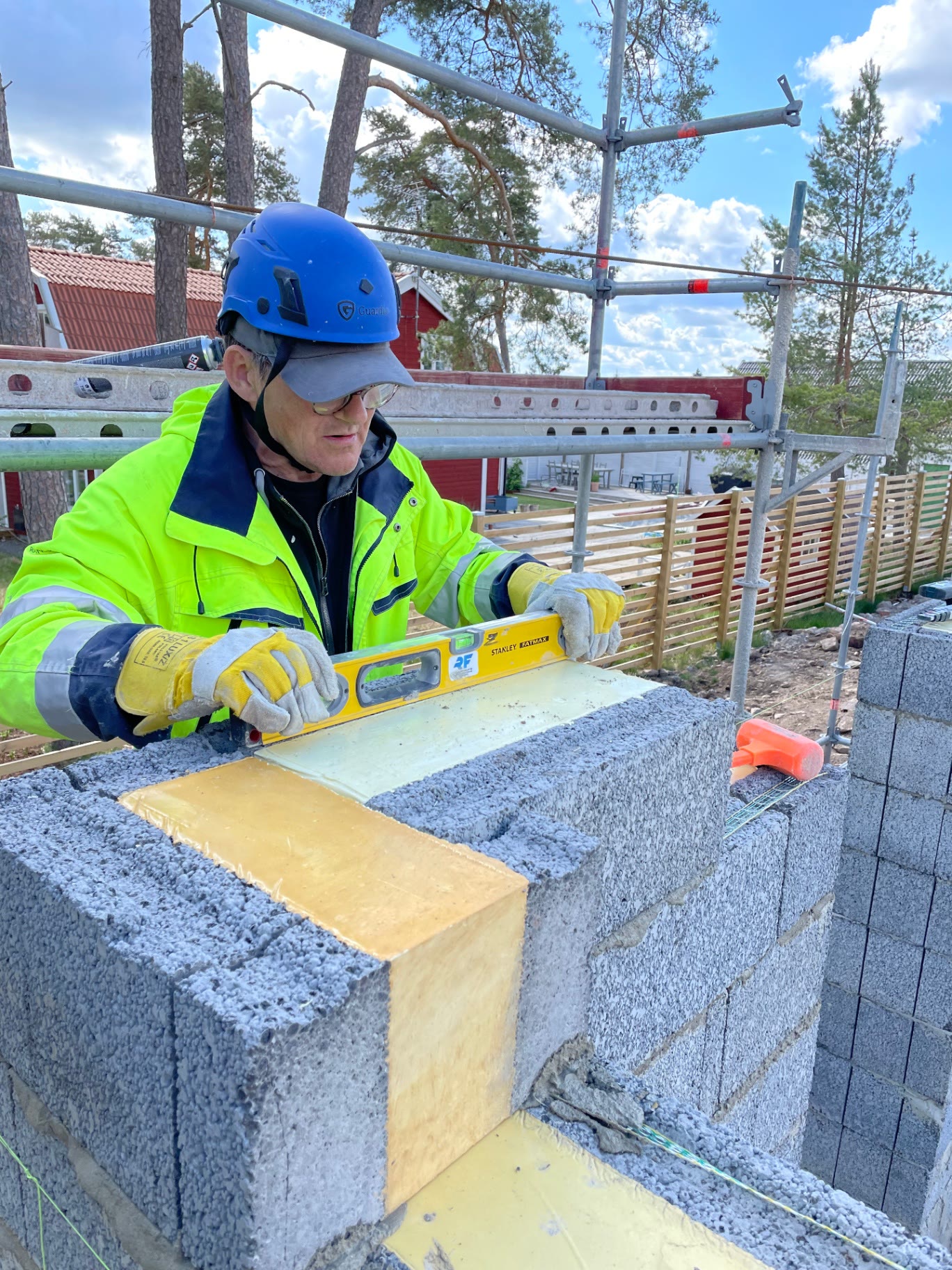 Bricklayer levelling an insulated lightweight concrete block