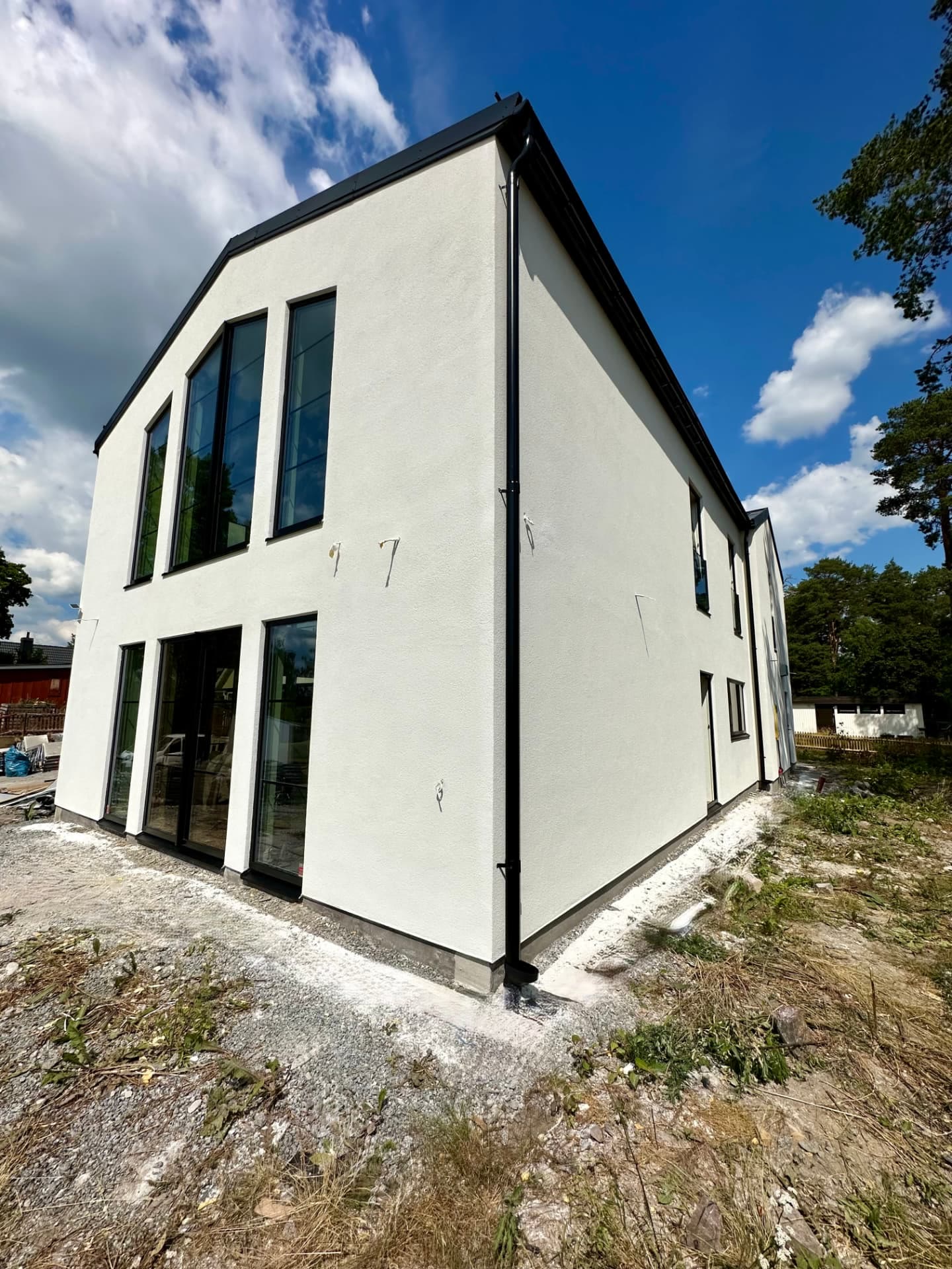 Large white rendered two-storey private house with tall black-framed glazing