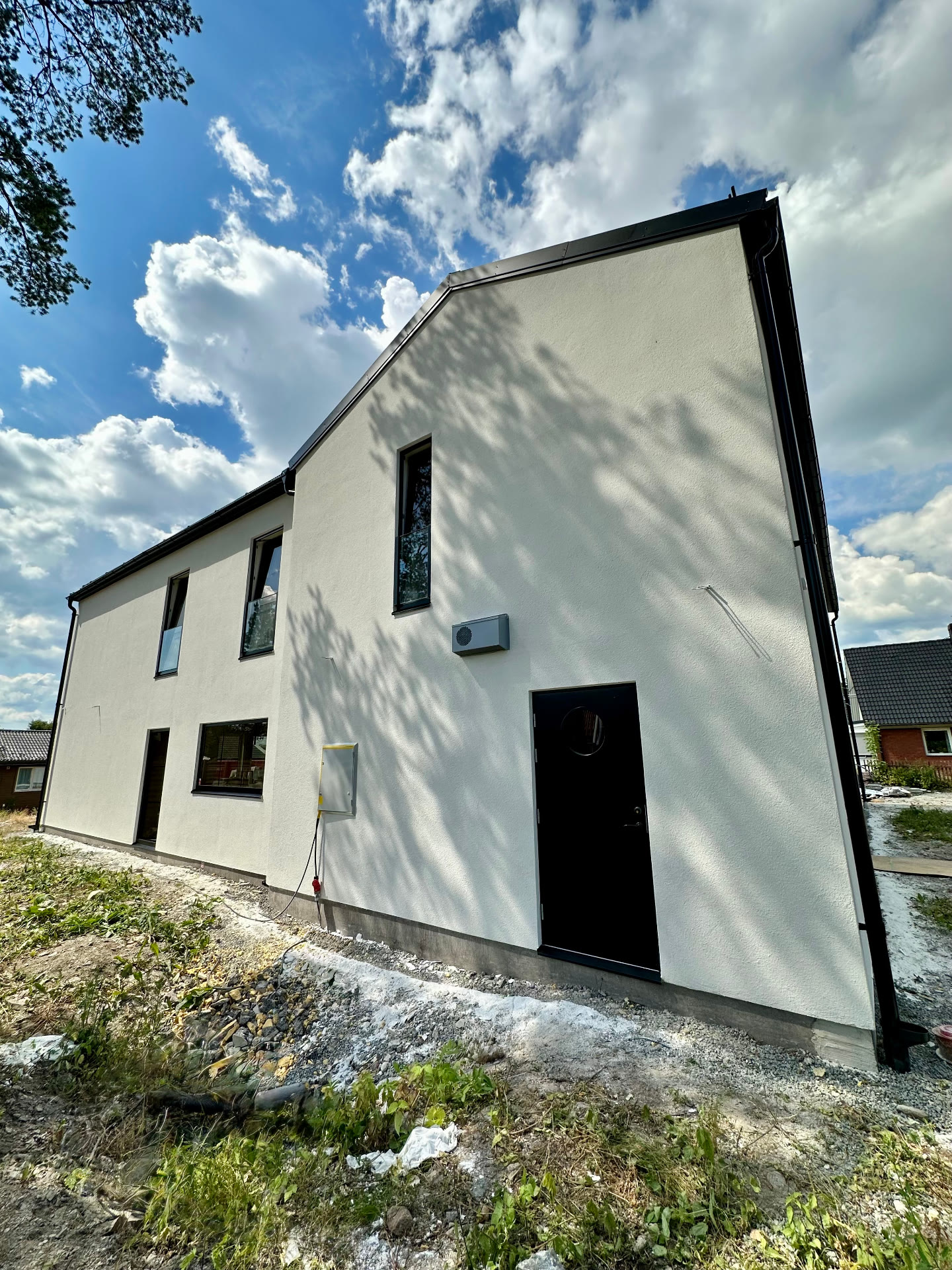 Large white rendered two-storey private villa with tall black-framed windows under a blue sky