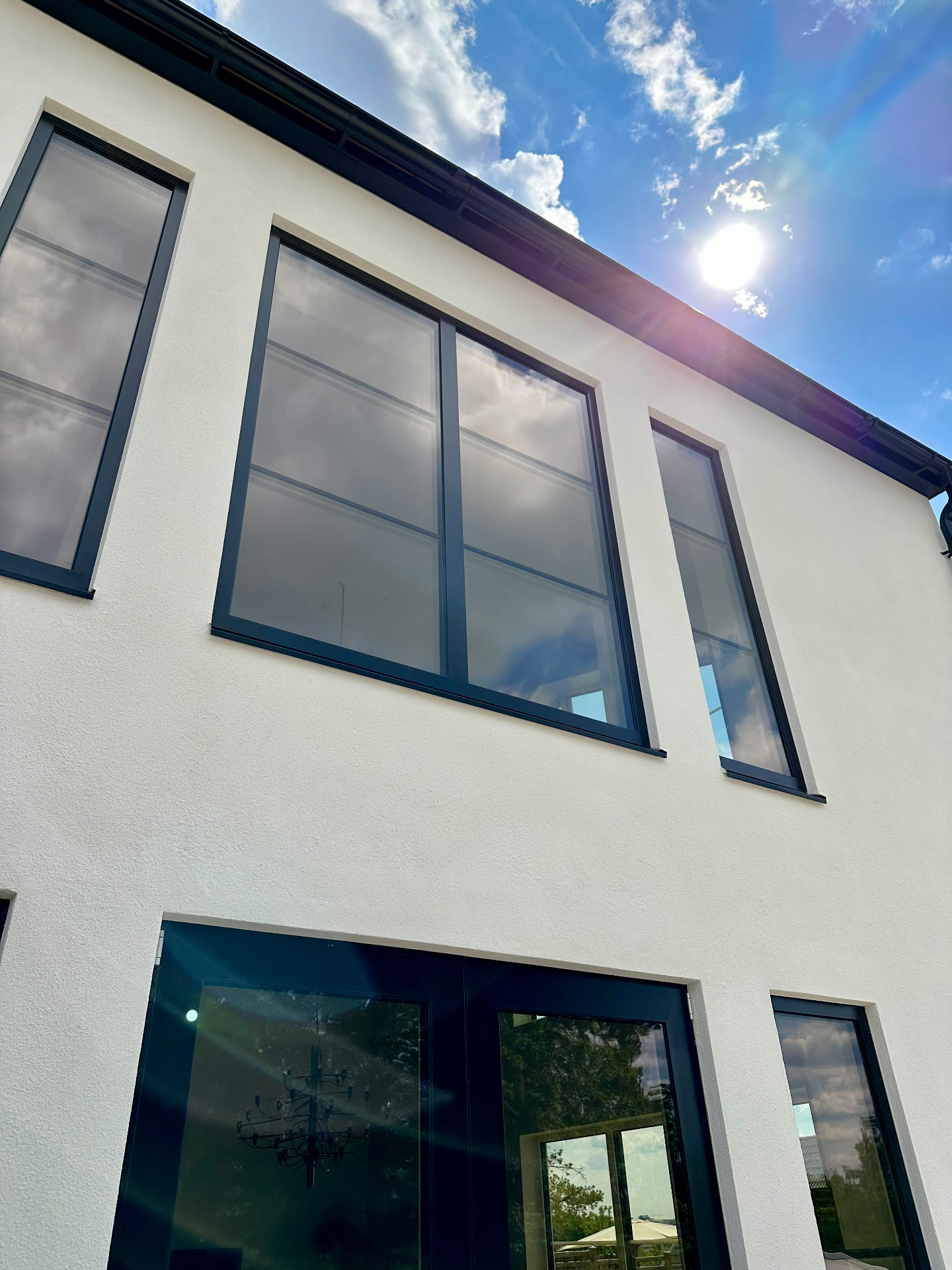 Upper-floor windows with black frames set into the white rendered facade